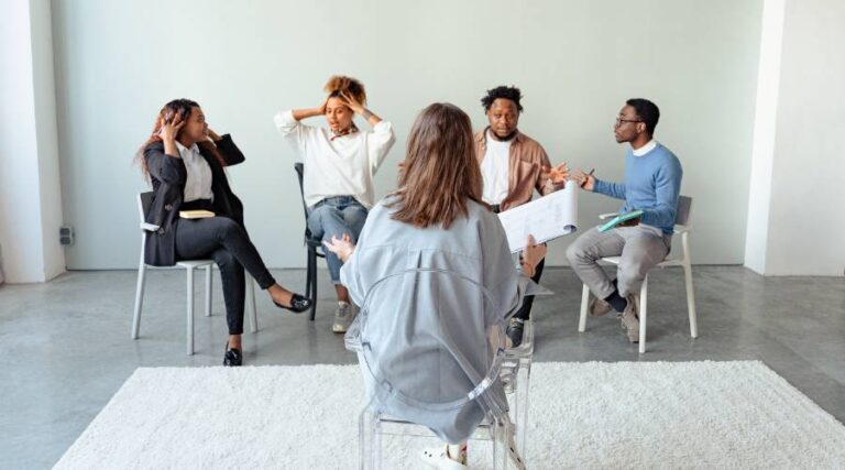 L'immagine rappresenta una valutazione delle competenze in azienda: una donna sta facendo un assessment a quattro persone.