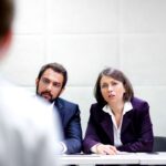 Una candidata è di fronte a tre selezionatori. Rappresenta la difficoltà della selezione da parte di entrambe le parti