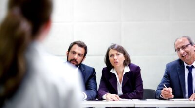 Una candidata è di fronte a tre selezionatori. Rappresenta la difficoltà della selezione da parte di entrambe le parti
