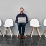 Il candidato ideale è seduto su una sedia con un pc sulle gambe; ai suoi lati ci sono 4 sedie vuote