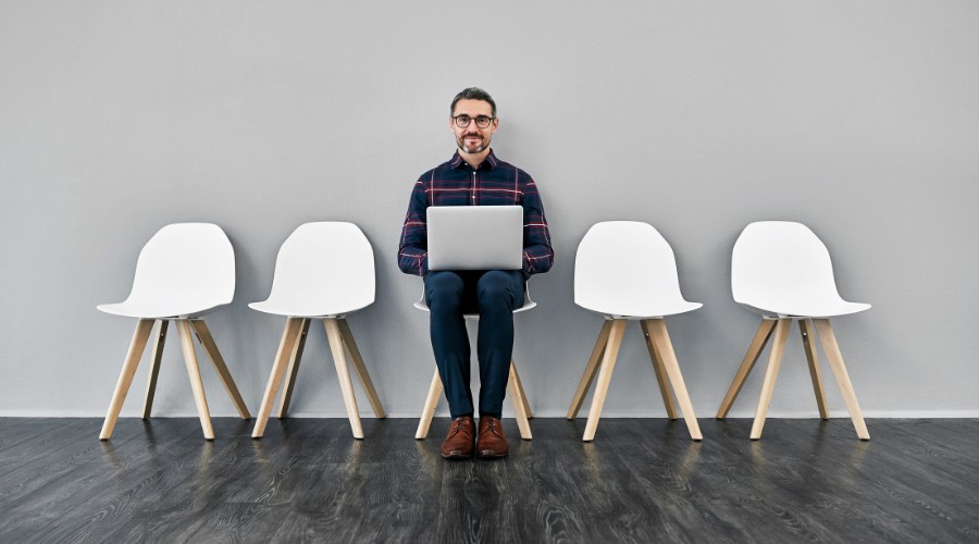Il candidato ideale è seduto su una sedia con un pc sulle gambe; ai suoi lati ci sono 4 sedie vuote