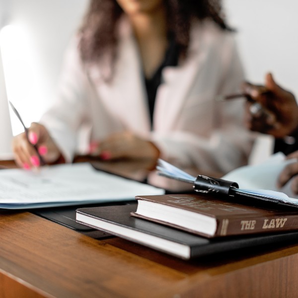 Ricerca Office Manager: una segretaria sta parlando con un partner di fronte a dei libri di legge e fogli su un tavolo