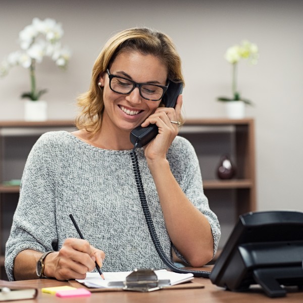 Ricerca Office Manager: una segretaria sta rispondendo al telefono alla sua scrivania