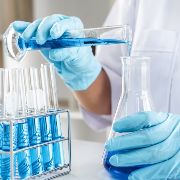 Un responsabile di produzione versa una fiala in un becker