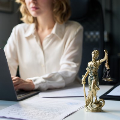 Selezione head of legale: una general counsel al computer con a fianco una statuetta della giustizia