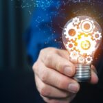 in primo piano una lampadina con degli ingranaggi